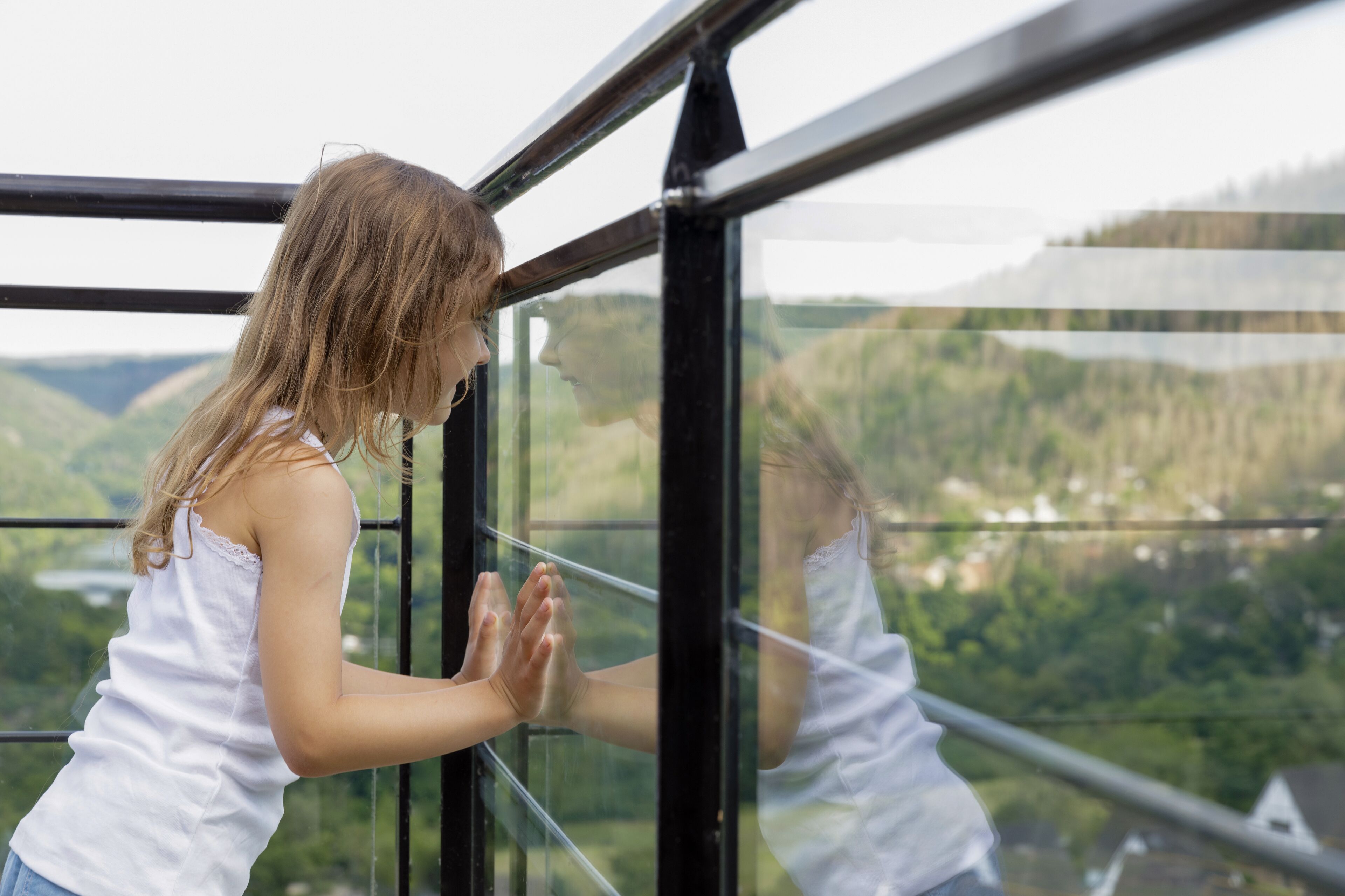 Eine Person steht an einem Fenster mit Blick auf eine grüne Landschaft.