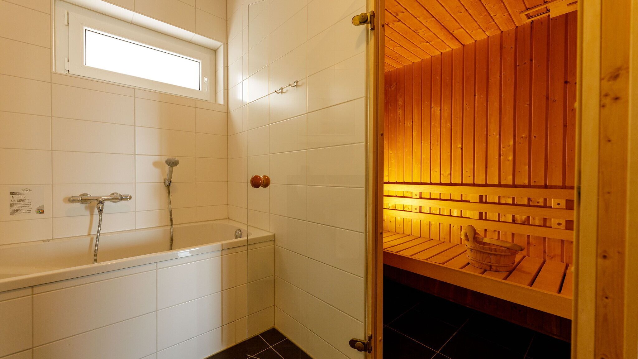 Un baño con bañera, ducha y zona de sauna de madera.