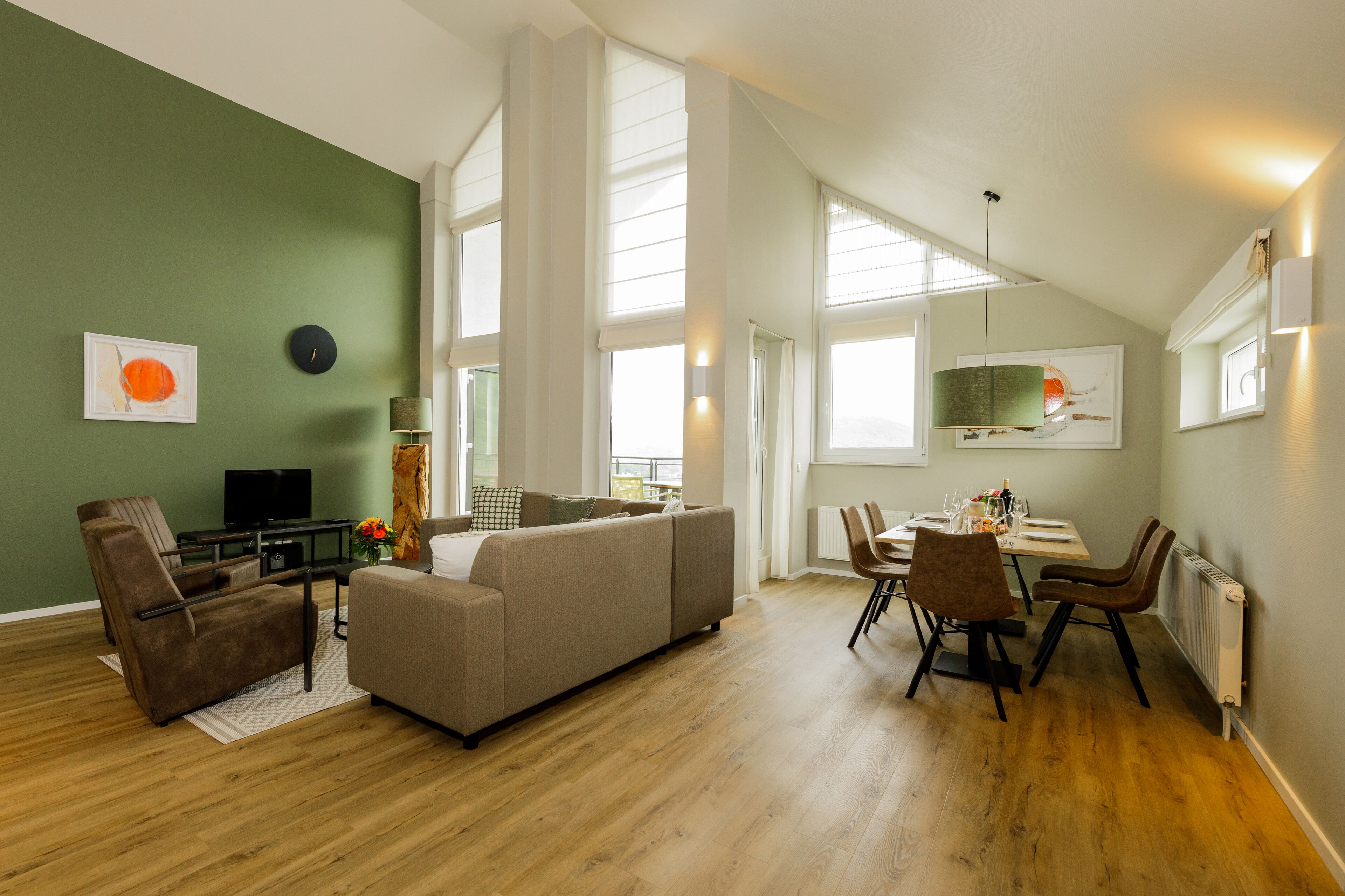 A spacious living area with a sofa, chairs, a dining table, and a television.