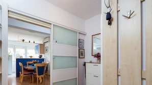 Una stanza con una porta scorrevole in vetro che dà su un'area pranzo, un armadio in legno e uno specchio a parete.