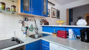 Una cucina con mobili azzurri, un lavello, un fornello e diversi oggetti da cucina sul piano di lavoro.