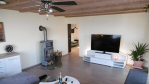 Un salon moderne doté d’une cheminée, d’un téléviseur à écran plat et d’un ventilateur de plafond.