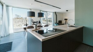 Een moderne keuken met een centraal eiland, een eethoek met stoelen en uitzicht op de omgeving.