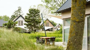 Een woonwijk met moderne huizen, een eettafel met stoelen en een boom op de voorgrond.