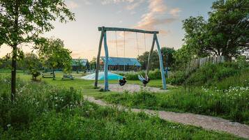 Eine Schaukel im Park, im Hintergrund ein Gebäude.