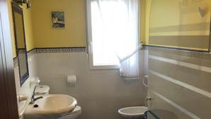 Un baño con suelo de mármol, dos inodoros, un lavabo y zona de ducha.