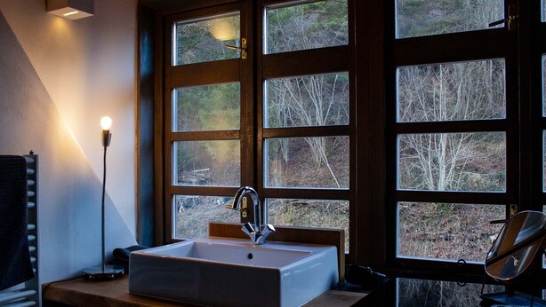 Une salle de bain avec une grande fenêtre, un lavabo et un lampadaire.