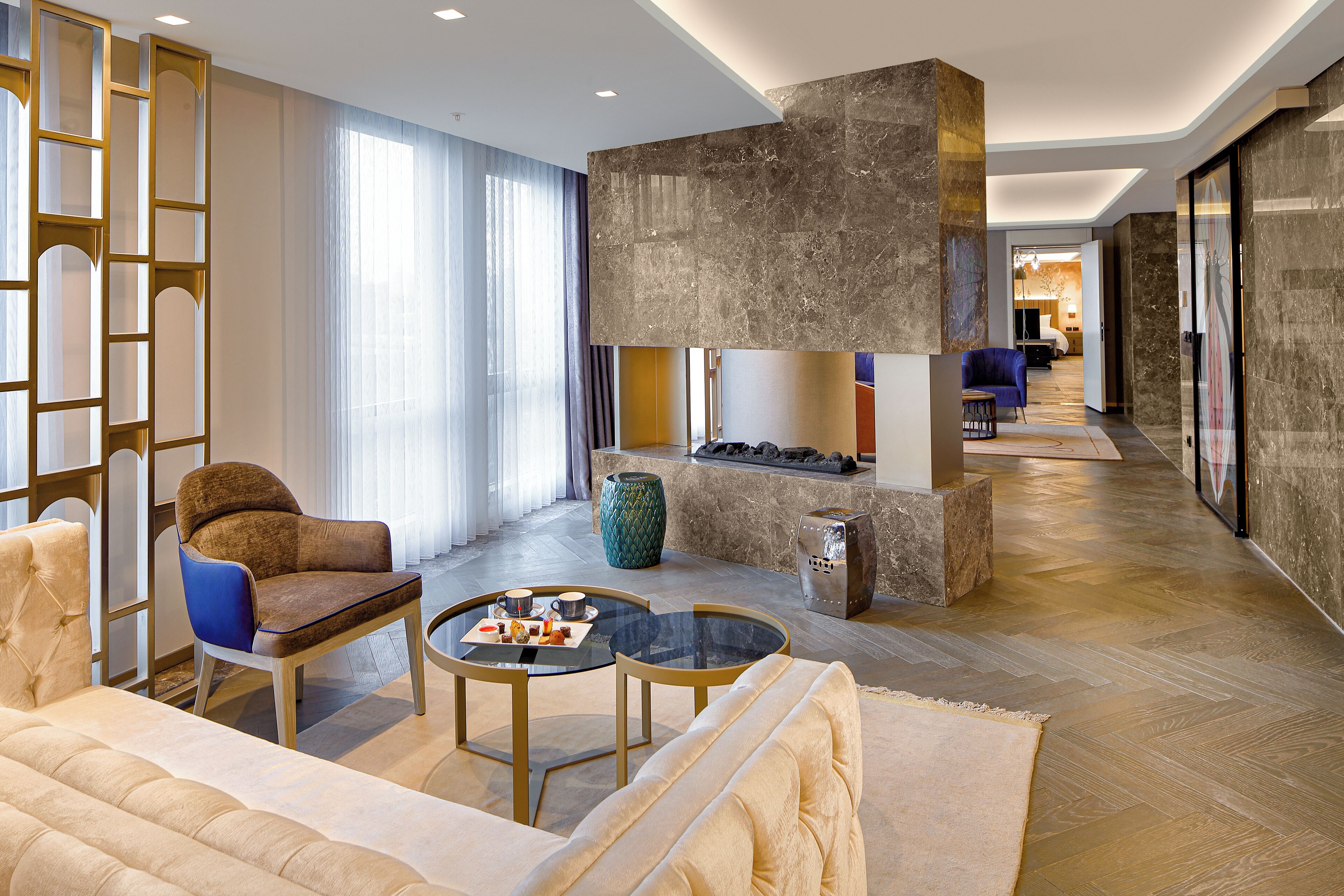 Een moderne hotellobby met een zithoek, een open haard en een gang naar een andere kamer.