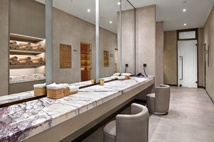 Un baño moderno con tocador de mármol, toalleros y un espejo grande.
