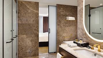 A modern bathroom with a marble floor, a large mirror, a vanity with a sink, and a shower area.