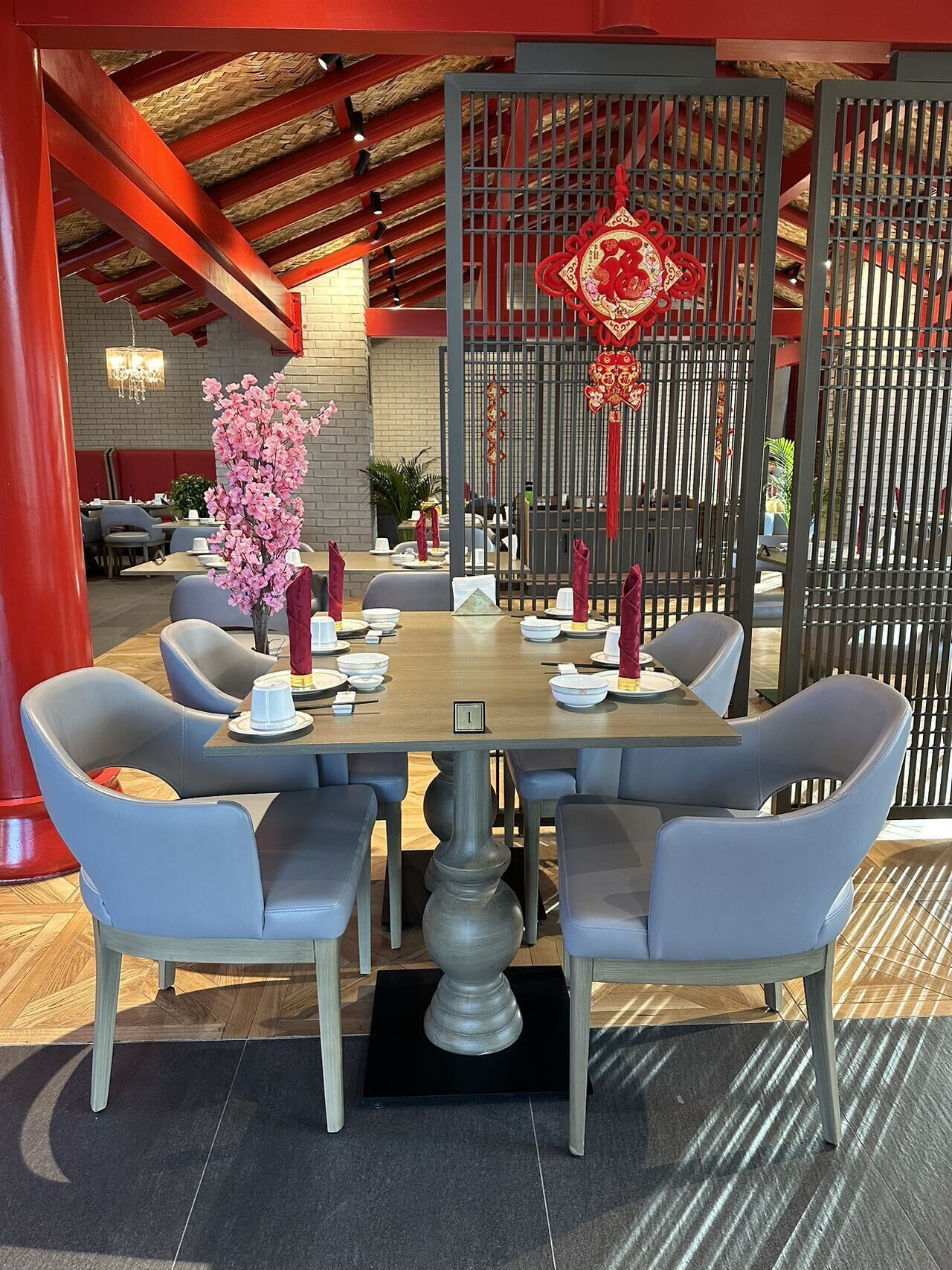 A dining area with a table set for four, surrounded by grey upholstered chairs.