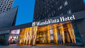 A tall hotel building with a modern design, featuring a prominent entrance and a clear sky in the background.