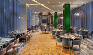 A spacious restaurant with multiple dining areas, a patterned carpet, and modern lighting fixtures. - Wanda Vista Istanbul (Istanbul)