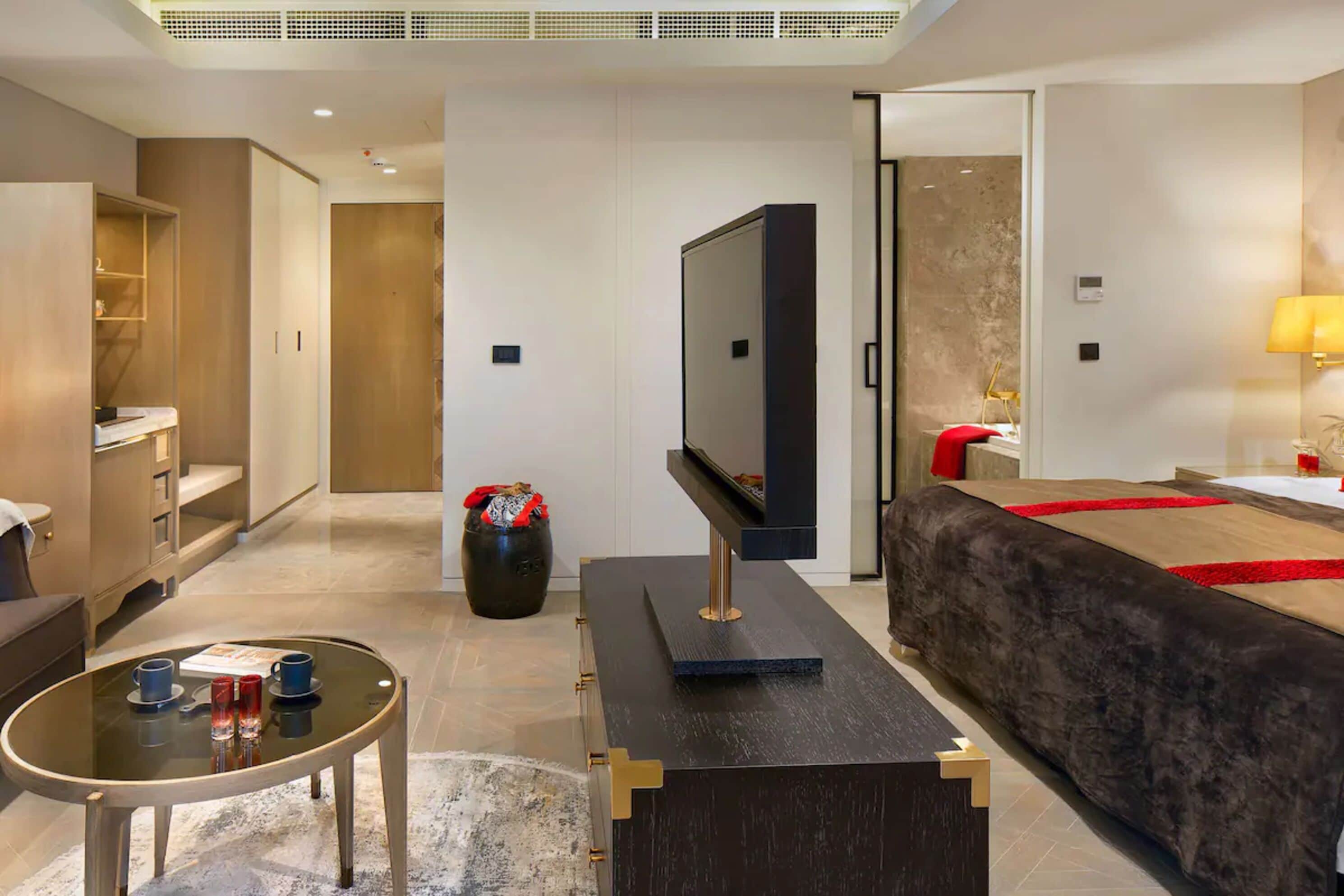 A modern hotel room with a flat-screen TV, a sofa, a coffee table, and a small side table.