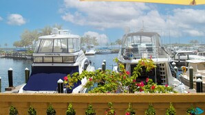 Un port de plaisance où plusieurs bateaux sont amarrés, un ciel dégagé et un parasol jaune.