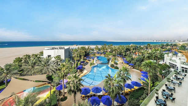 Ein Resort mit Pool, Palmen und Blick auf den Strand.