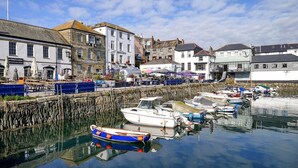A harbor with boats docked, a stone pier, and buildings with signs like "Quay Inn" and "The Stable."