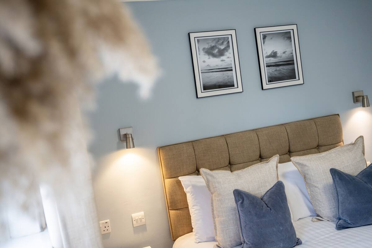Ein Schlafzimmer mit Kopfteil, Kissen und zwei gerahmten Bildern an der Wand.