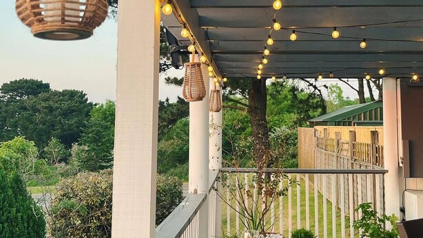 A covered outdoor area with a table and chairs, string lights, and potted plants.