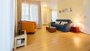 Un salon avec un plancher en bois, un canapé, un fauteuil, une table basse et un meuble pour la télévision.
