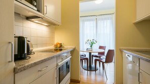 Une cuisine compacte équipée d’un four à micro-ondes, d’une bouilloire et d’une petite table à manger avec des chaises.