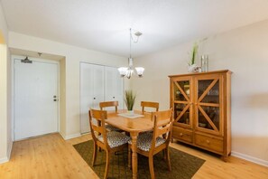 A dining area with a wooden table and chairs, a chandelier, a cabinet, and a door. - The desirable Marco Island community - South Seas (Marco Island)