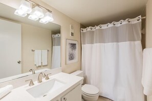 A bathroom with a large mirror, two sinks, a toilet, and a shower curtain. - The desirable Marco Island community - South Seas (Marco Island)