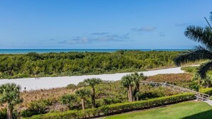A coastal landscape with a sandy beach, dense greenery, and a wooden bridge. - Located in the desirable Marco Island community of South Seas (Marco Island)