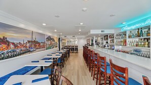 Zona de bar con un letrero de neón que dice "Chesapeake Bay" y un mural de un paisaje urbano en la pared.