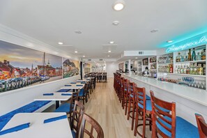 Zona de bar con un letrero de neón que dice "Chesapeake Bay" y un mural de un paisaje urbano en la pared.