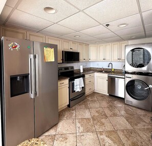 Cozinha equipada com eletrodomésticos de aço inoxidável, incluindo geladeira, micro-ondas, forno, lava-louças e máquina de lavar.