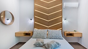 Une chambre à coucher moderne, équipée d’un lit, de tables de chevet, d’un miroir et d’un appareil de climatisation.
