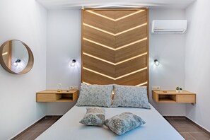 A modern bedroom with a bed, bedside tables, a mirror, and an air conditioning unit.