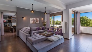 Un vaste espace de vie comprenant un canapé gris, une table basse et un coin repas avec une table et des chaises.
