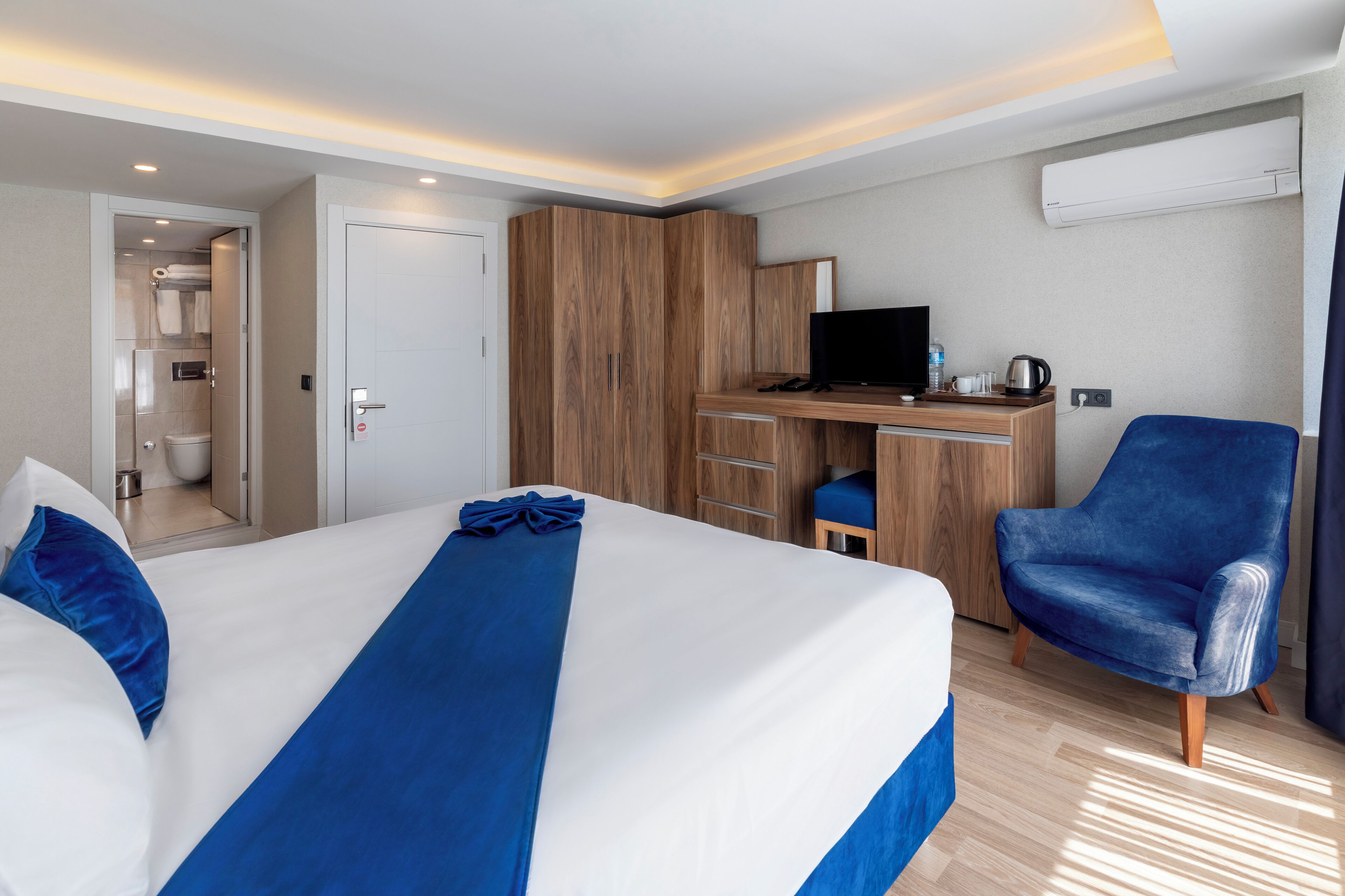 Habitación de hotel con una cama grande, un escritorio con computadora, una silla y zona de ducha.