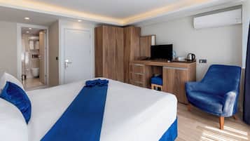 Habitación de hotel con una cama grande, un escritorio con computadora, una silla y zona de ducha.
