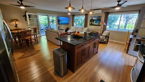 A spacious kitchen with wooden flooring, a central island, and ceiling fans.