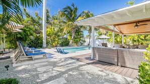 Un espace aménagé au bord de la piscine, avec des chaises longues, un bar et un coin salon abrité.
