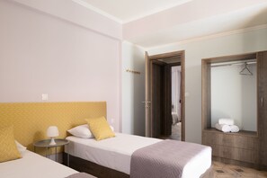 A hotel room with two beds, a wardrobe, and a mirror.