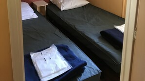 A compact room with two single beds, a small table, and a window with curtains. - Mobil Home 6 Personnes, 3 Chambres et Terrasse Couverte (Boofzheim)