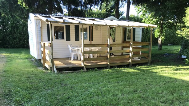 A small wooden structure with a porch, white plastic chairs, and a table. - Mobil Home 6 Personnes, 3 Chambres et Terrasse Couverte (Boofzheim)