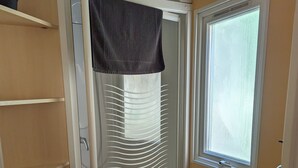 A compact bathroom with a shower enclosure, a window, and a small sink. - Mobil Home 6 Personnes, 3 Chambres et Terrasse Couverte (Boofzheim)