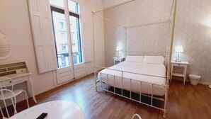 Een kamer met een bed, nachtkastjes, een bureau en een raam.
