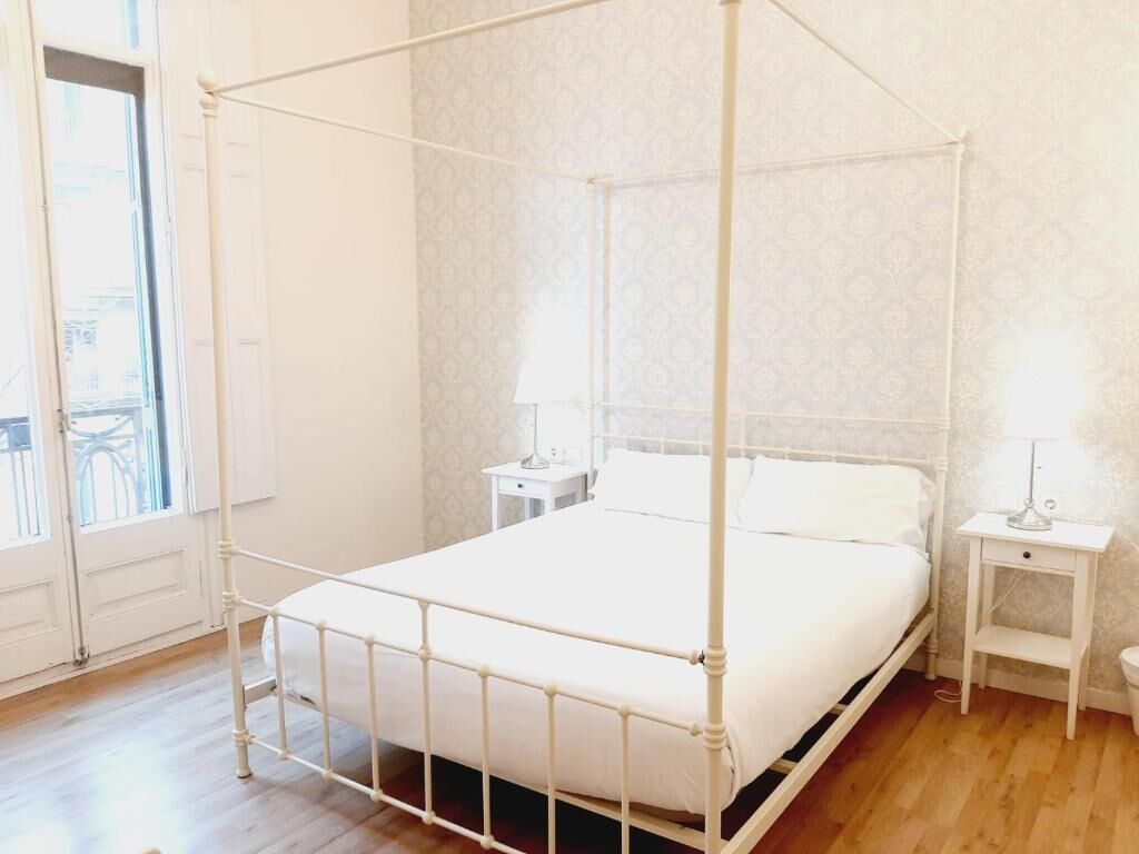 Ein weißes Himmelbett in einem Zimmer mit strukturierter Tapete und Holzboden.