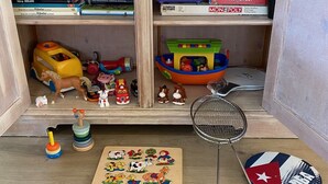 A wooden cabinet with shelves containing books, toys, and a puzzle mat. - Quiet recreation house in Zeeland with Netflix 2 (Bruinisse)