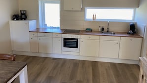 A compact kitchen with white cabinets, a built-in oven, a sink, and a window providing natural light. - Quiet recreation house in Zeeland with Netflix 2 (Bruinisse)