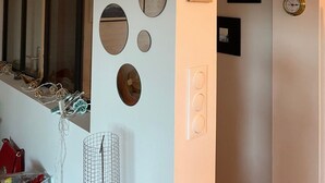 Ein Zimmer mit einem großen Spiegel, mehreren runden Wanddekorationen, einem Holunderschild und einer Wanduhr.