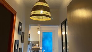 Ein Flur mit einer Hängeleuchte, einer Tür, die in eine Küche führt, und einem Fenster mit blauer Tönung.