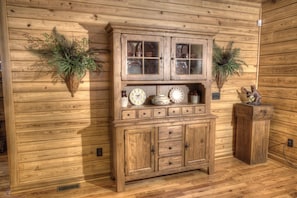 A stylish cabinet with multiple drawers and shelves, adorned with decorative items and surrounded by lush greenery.