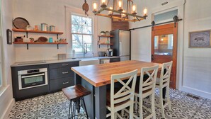 Una cocina con isla de madera, armarios negros y un refrigerador de acero inoxidable.